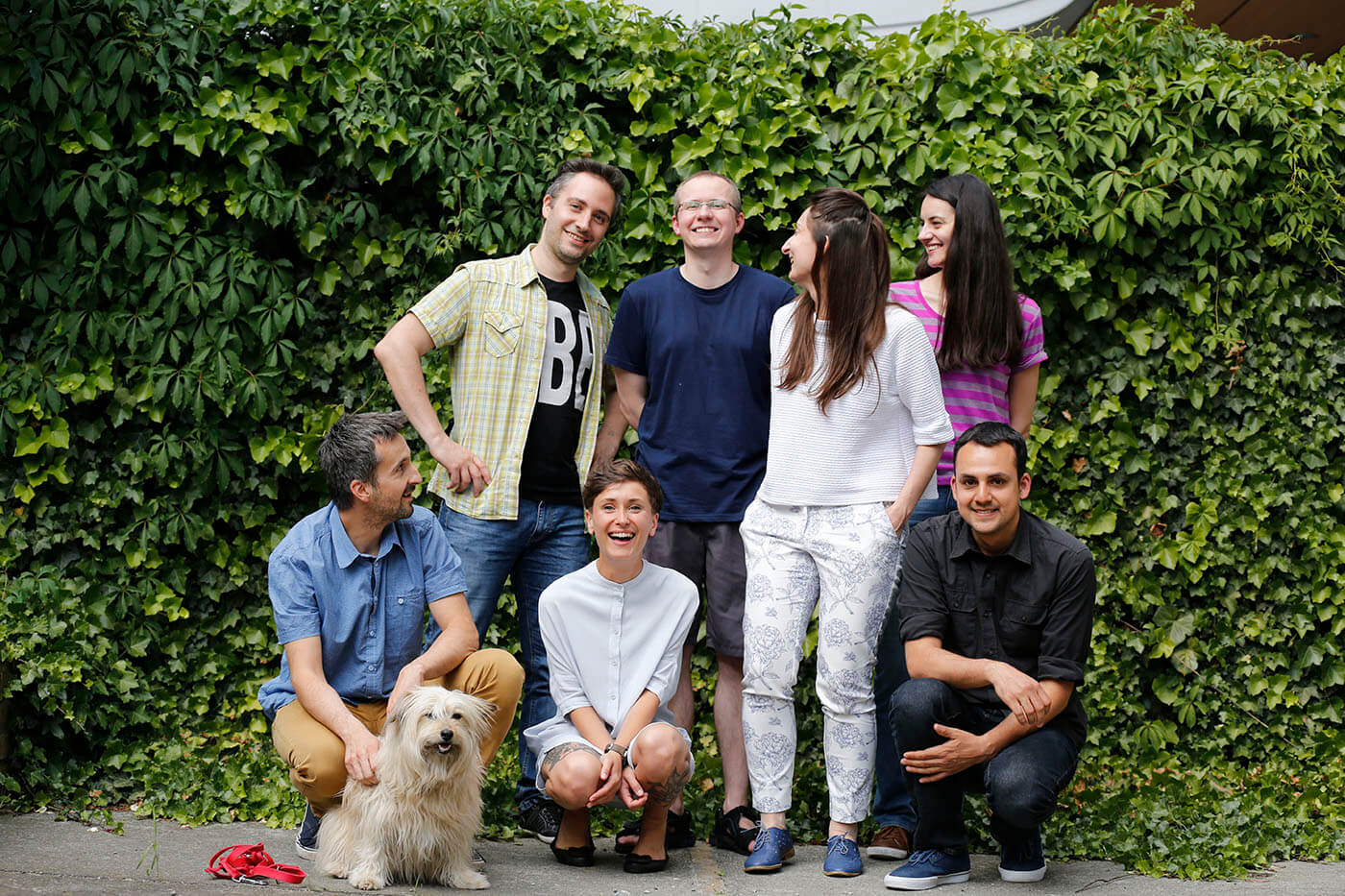 Group of kiwee employees standing in together in front of a bush