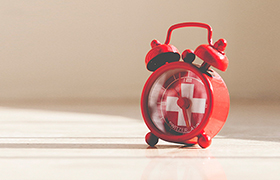Red alarm clock with white cross