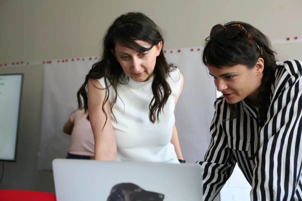 Zwei Frauen arbeiten während einer Brainstorming-Sitzung im Büro an einem Laptop.