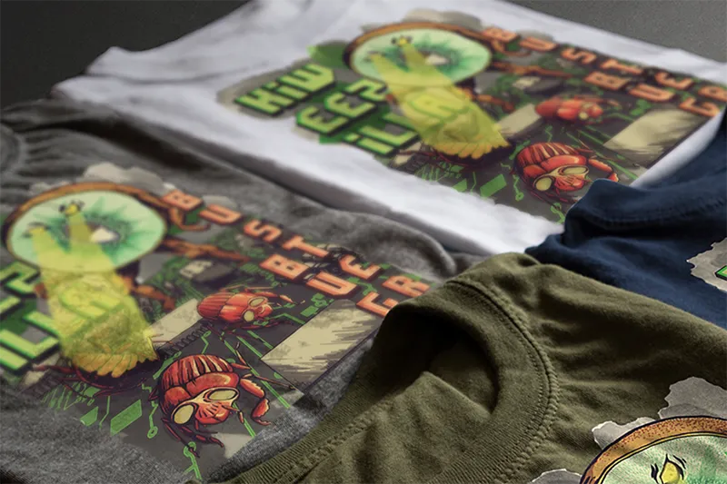 Vier farbenfrohe T-Shirts mit Kiweezilla-Motiven mit abstrakter Bildsprache sind auf einer dunklen Oberfläche aufgebracht. Der Druck umfasst Roboterfiguren, grüne Gitter und Textelemente in verschiedenen leuchtenden Farben.