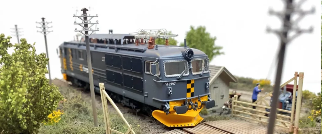 Detailed model electric locomotive number 14 2197 travelling through a miniature railway landscape
